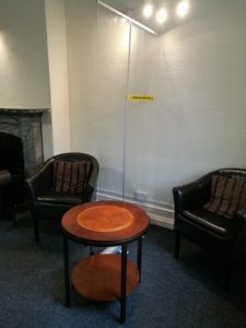 waiting room chairs with coffee table and protective screen between