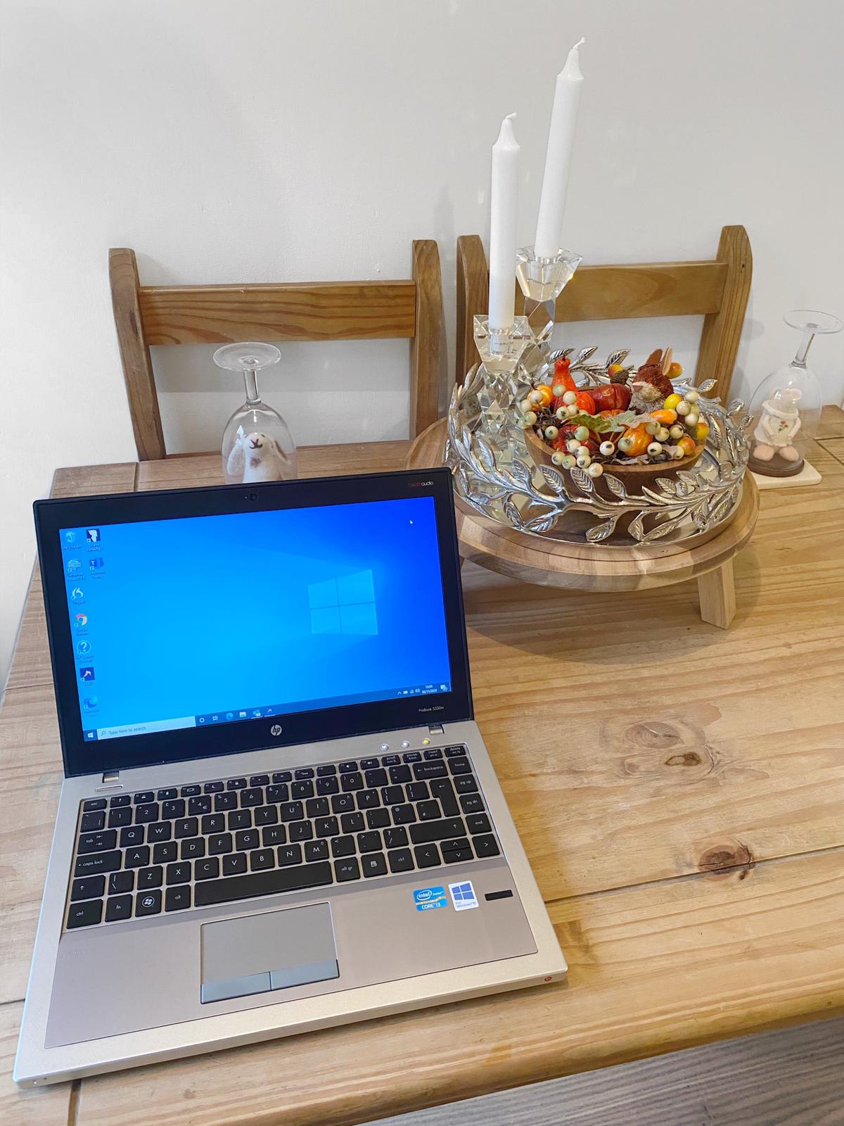Laptop on table next to decorative centre piece with candles