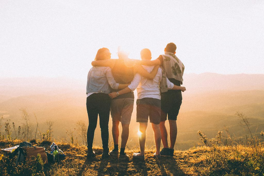 four-person-standing-on-cliff-in-front-of-sun