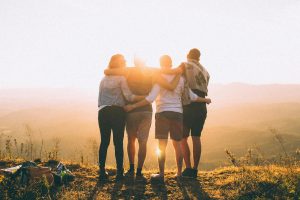 four-person-standing-on-cliff-in-front-of-sun