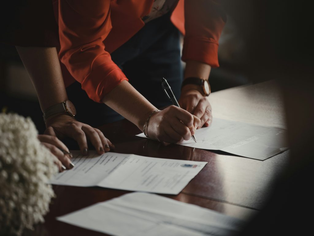 two people leaning on table and signing document